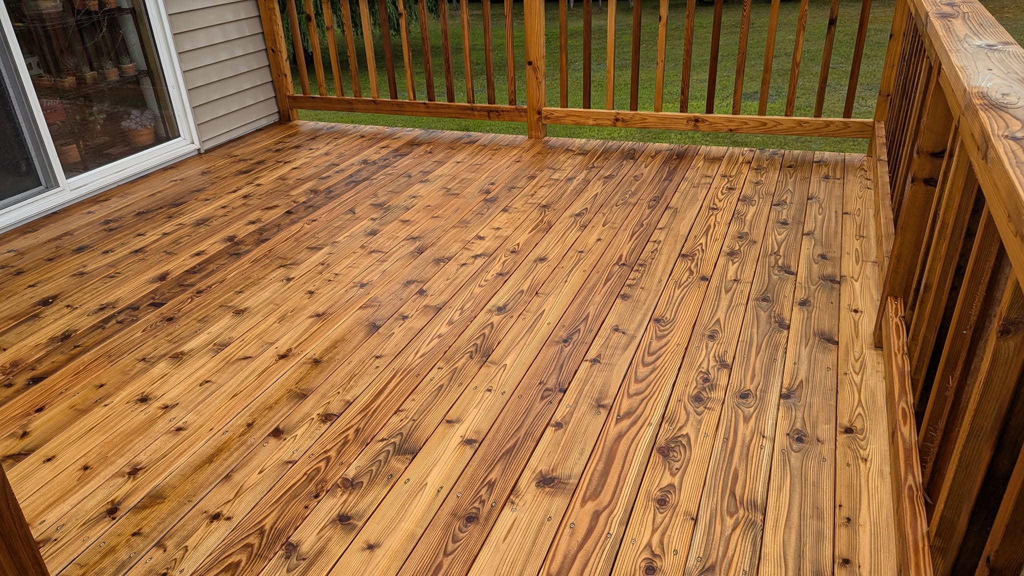 A freshly stained deck with railings overlooking the lawn