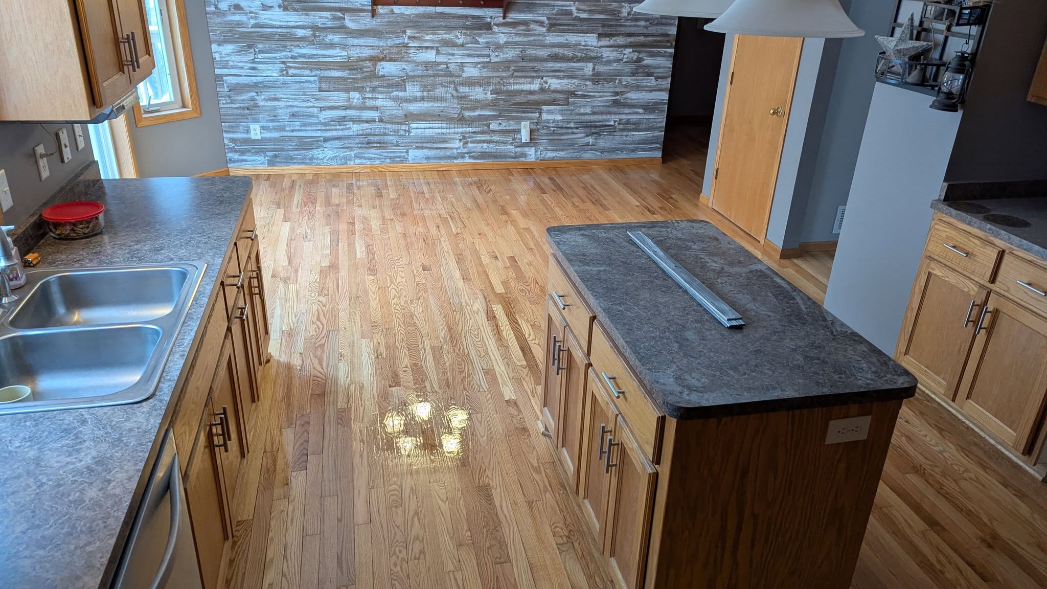 A kitchen refinished with a stone feature wall and hardwood floors
