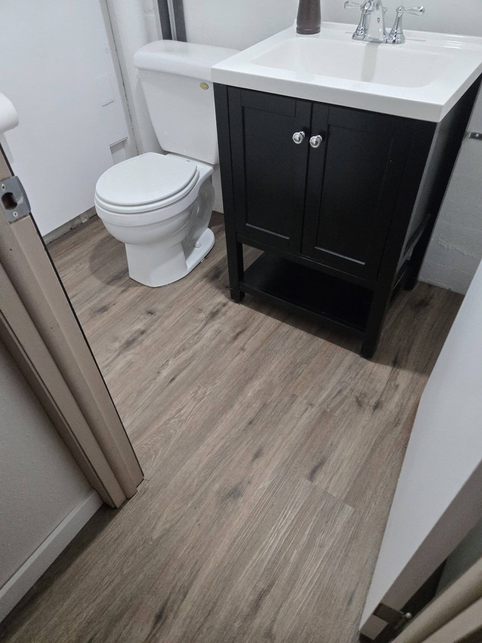 A bathroom finished with black and white hex tile and a stained door